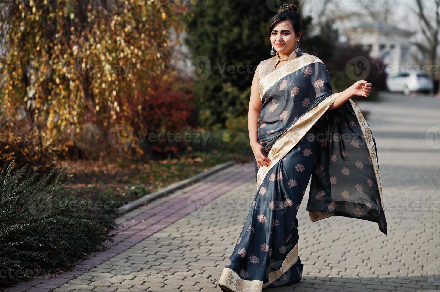 elegante morena chica india del sur de asia en sari caminando al aire libre. foto