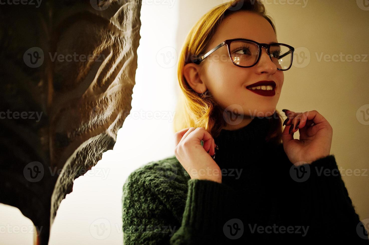 Cheerful young beautiful redhaired woman in glasses, wear on green warm wool sweater,  posed at cafe. photo