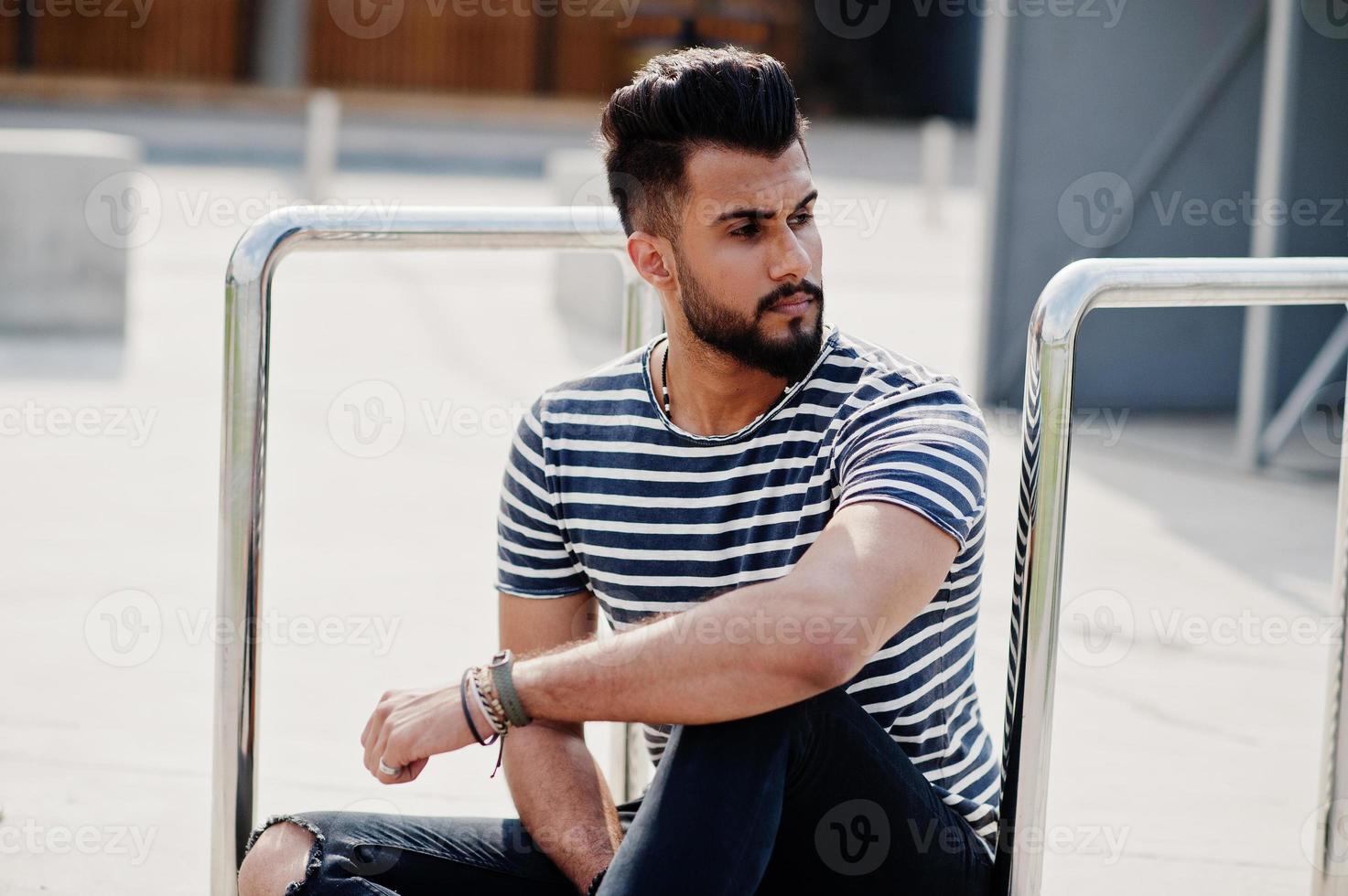 Handsome tall arabian beard man model at stripped shirt posed outdoor. Fashionable arab guy. photo