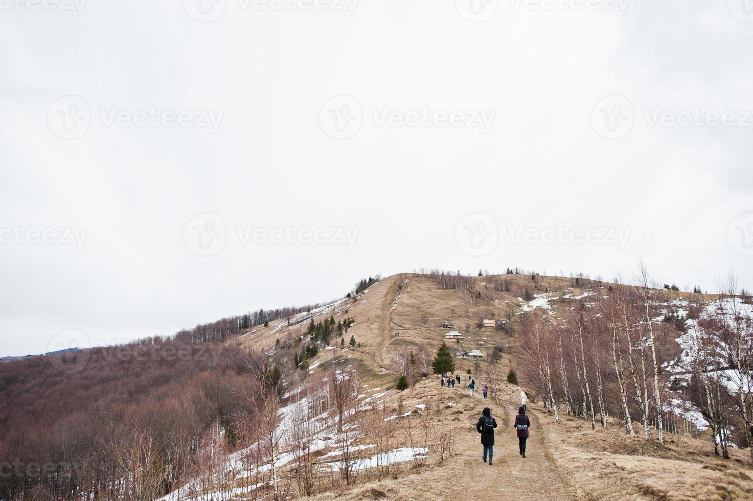 grupo de turistas haciendo senderismo en los valles nevados de las montañas de los cárpatos. vista de los cárpatos ucranianos y yaremche desde la cima de makovitsa. foto