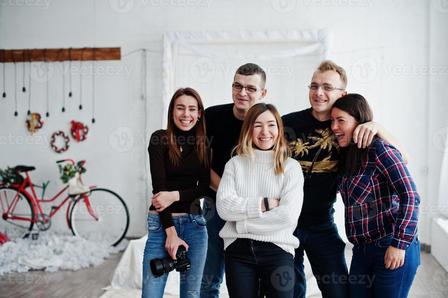 Group of five peoples, friends photographers and designers on studio shooting after hard work day. They happy and laughing. photo