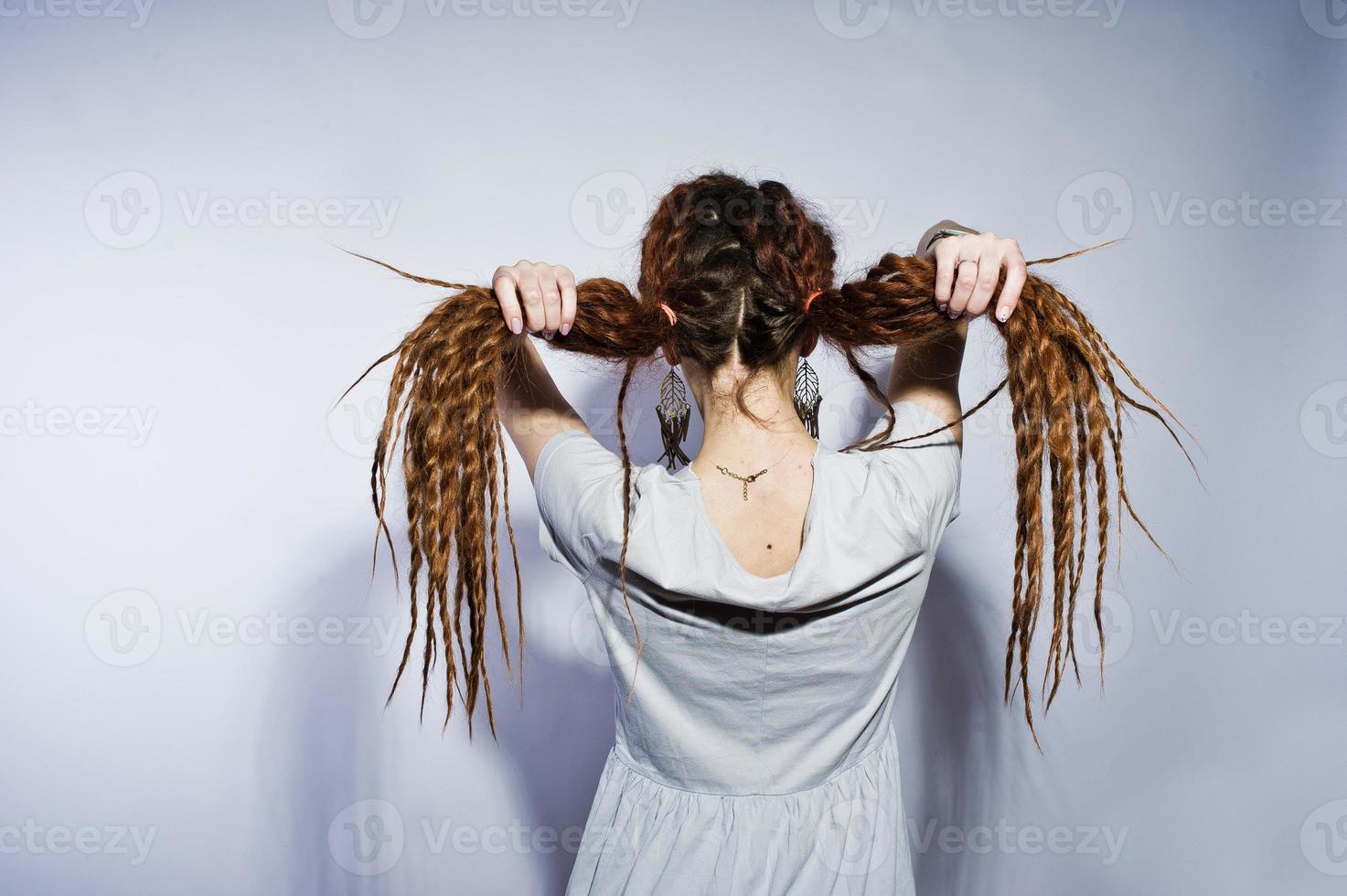 Studio shoot back of girl in gray dress with pigtails dreads on white background. photo