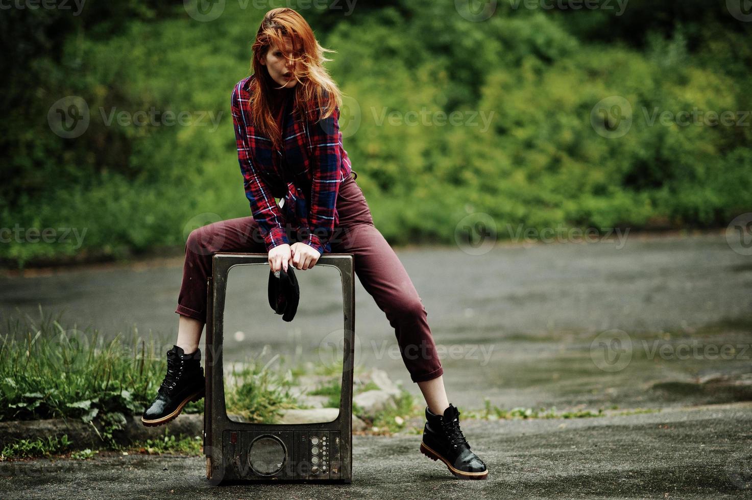 Fashion portrait of redhaired sexy girl outdoor. Model attractive dramatic woman with old tv box. photo