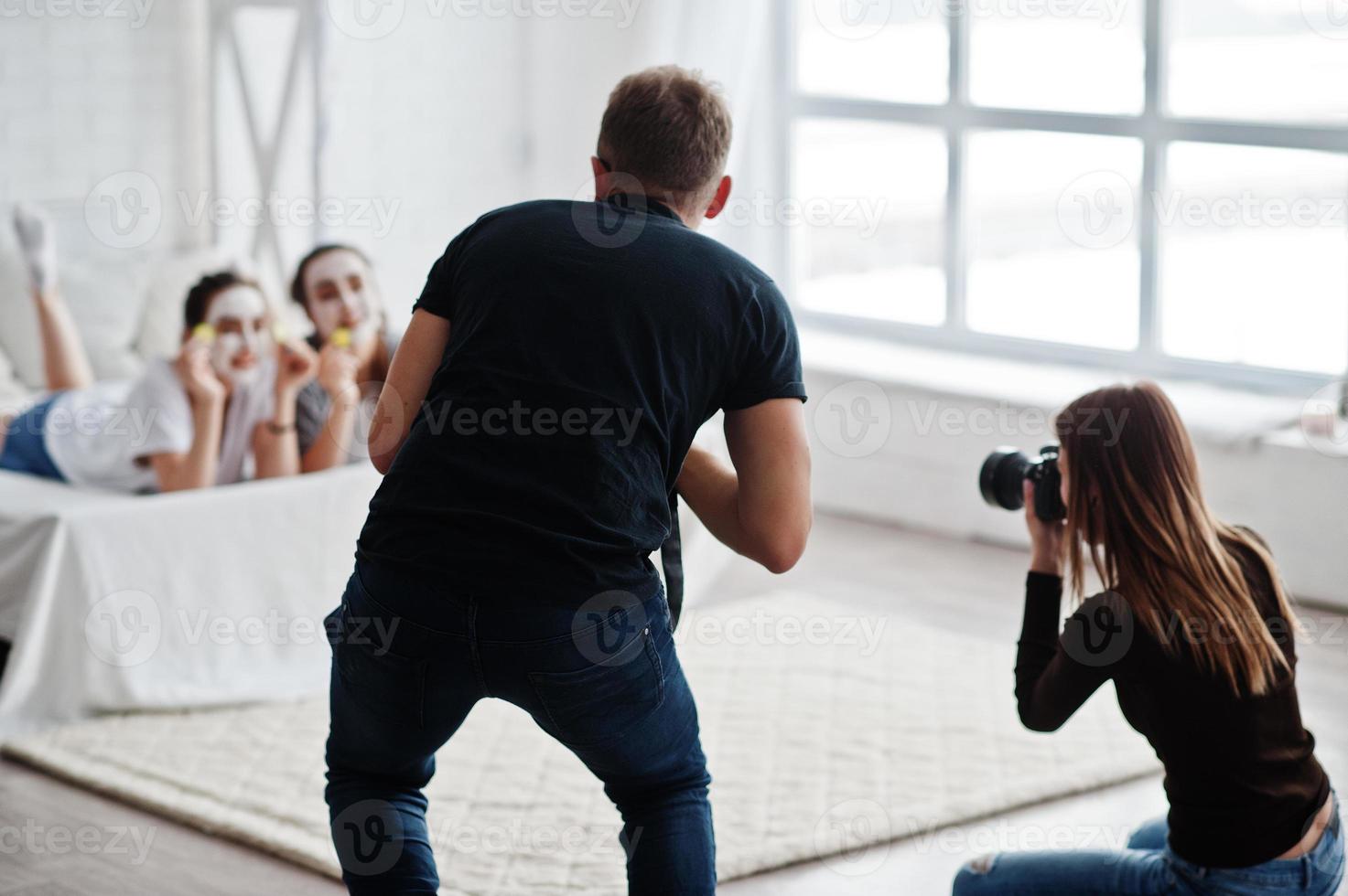 The team of two photographers shooting on studio twins girls while they make their own masks cream. Professional photographer on work. photo