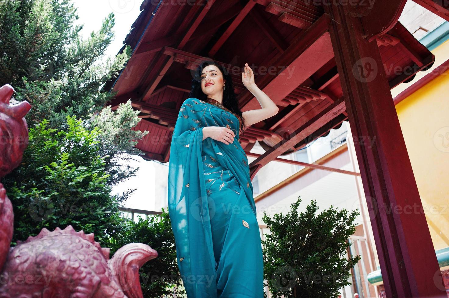 Portrait of beautiful indian brumette girl or hindu woman model against japanese traditional house and dragon figure. photo