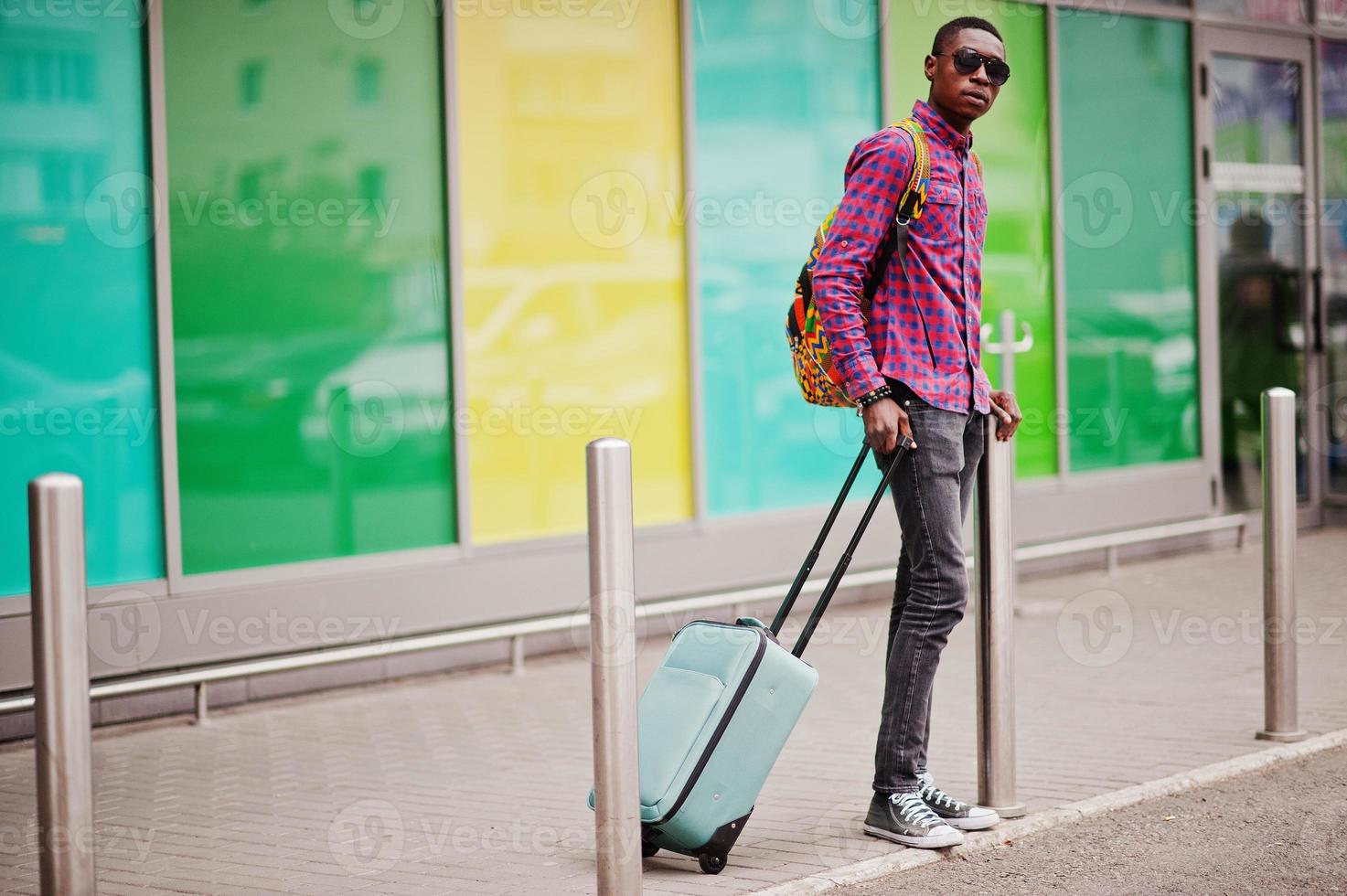 African american man in checkered shirt, sunglasses and jeans with suitcase. Black man traveler. photo