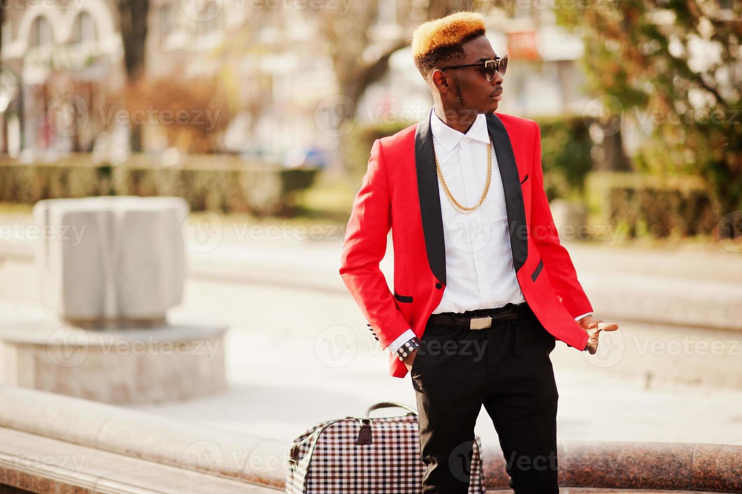 Fashion african american man model at red suit, with highlights hair and handbag posed at street. photo
