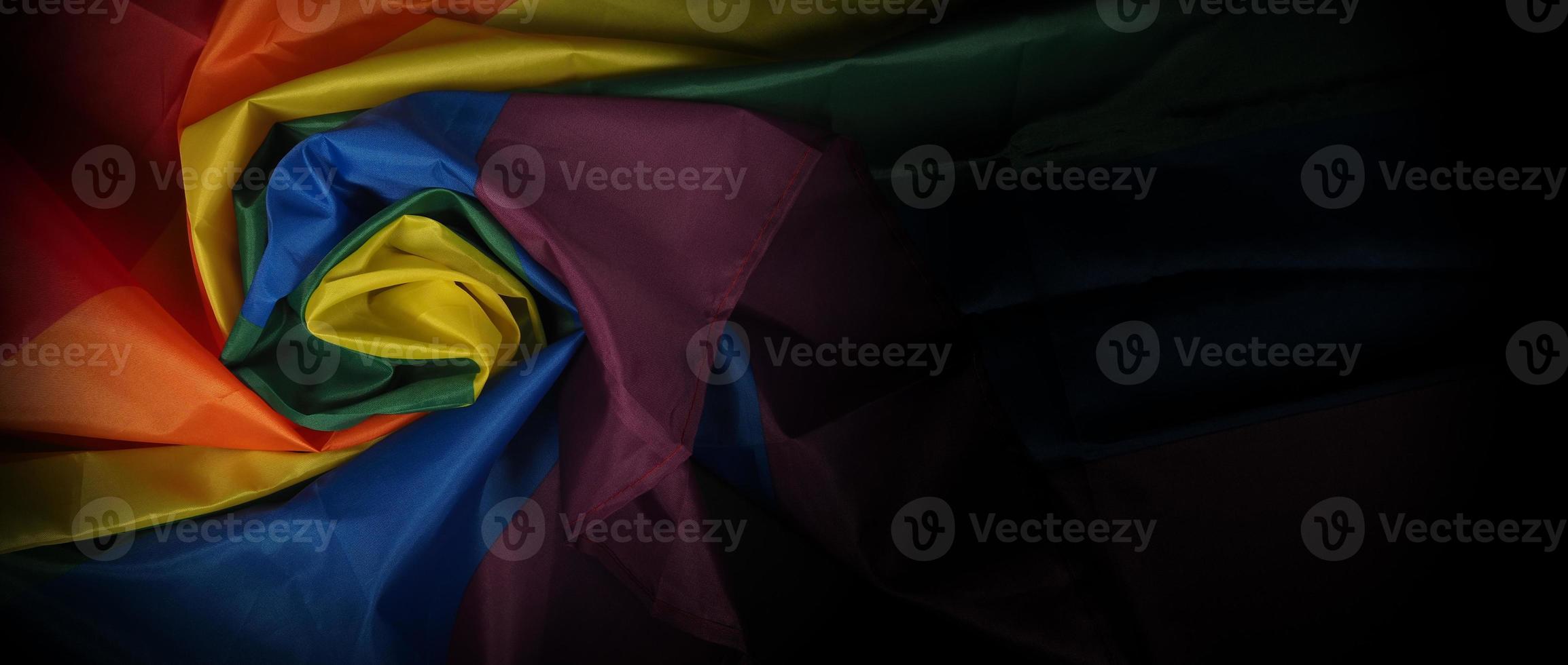 LGBTQ pride flag on black background. Lgbt rainbow flag in gay hand. photo