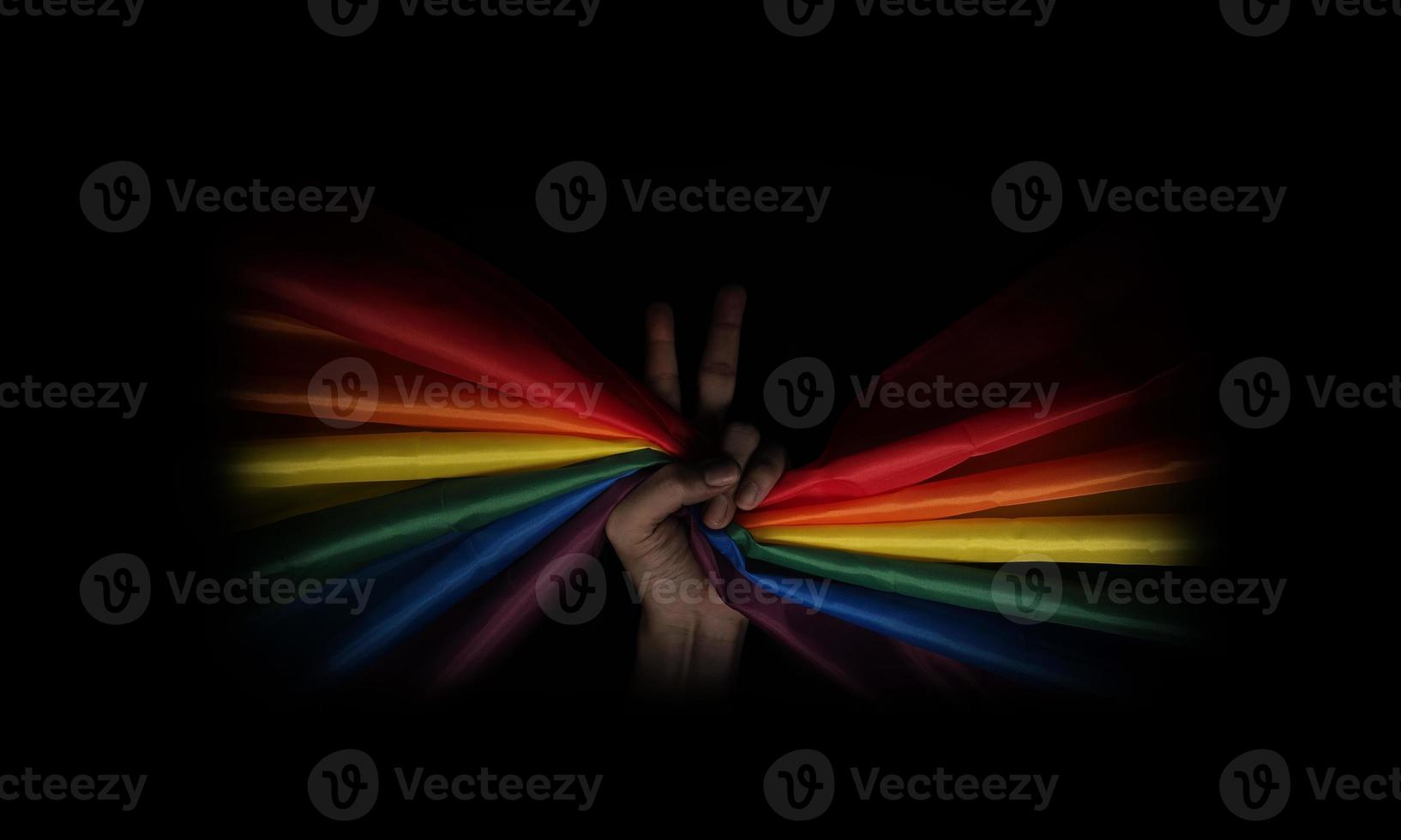 LGBTQ pride flag on black background. Lgbt rainbow flag in gay hand. photo