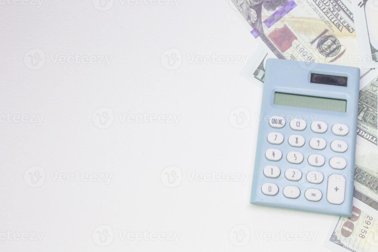calculadora azul y billetes en fondo blanco. foto