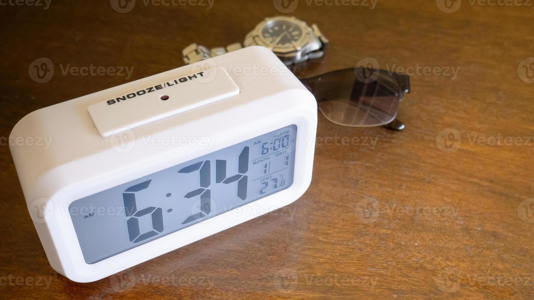 The white alarm clock digital numbers on wood table. photo