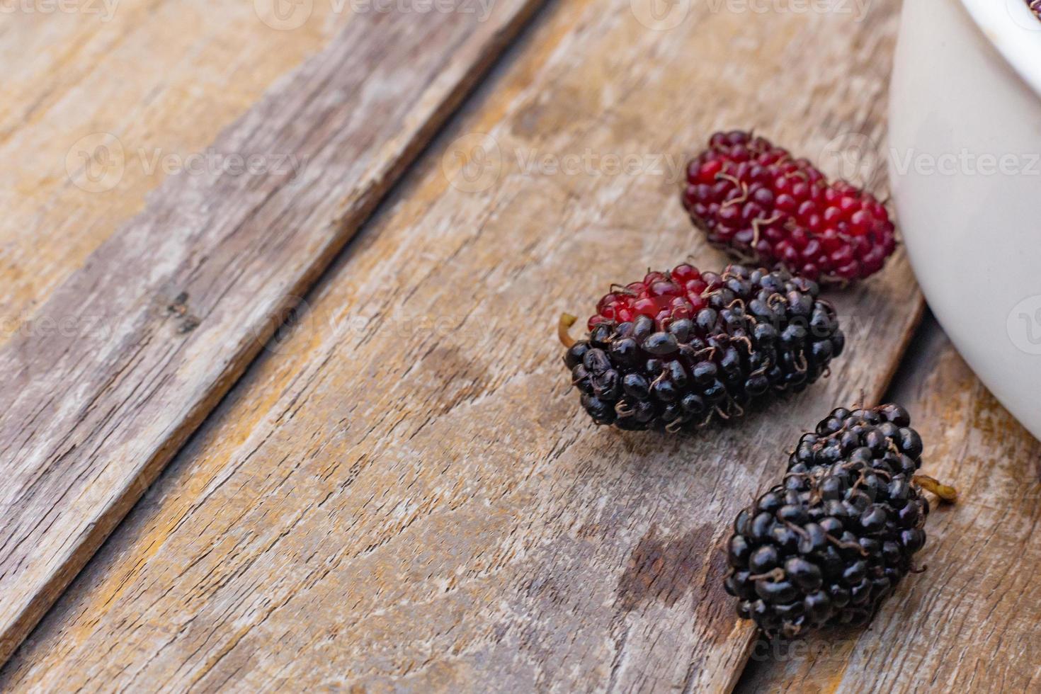 The mulberry fruit in white bowl on wood table. photo