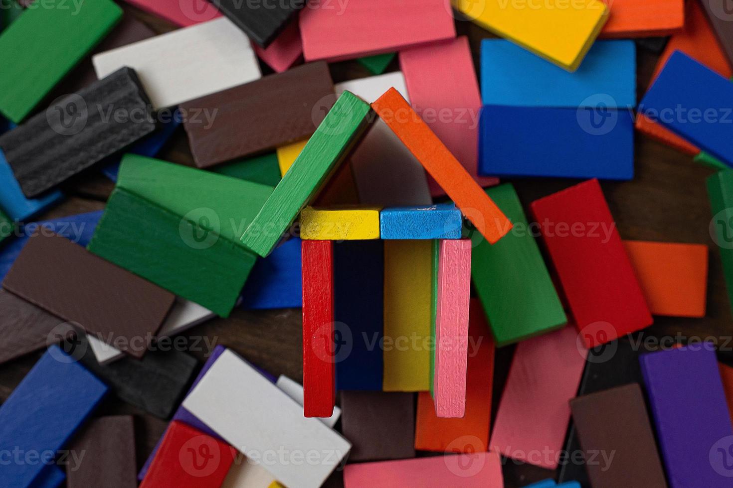 la imagen de la casa de construcción multicolor de dominó en la mesa de madera. foto