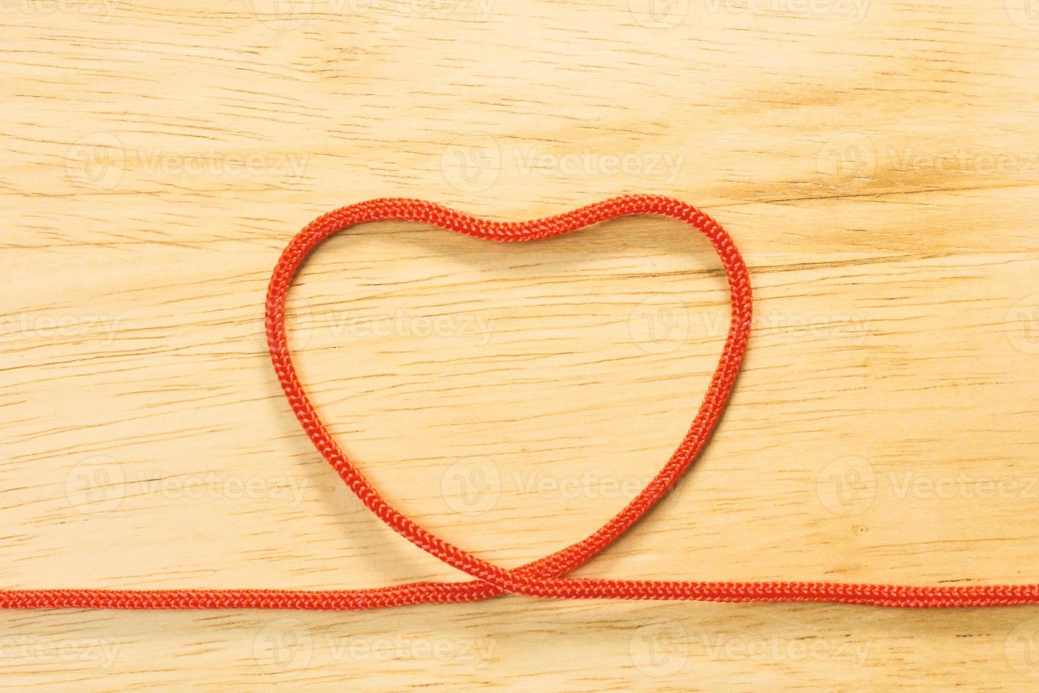 Red rope heart on wood plate valentine content. photo