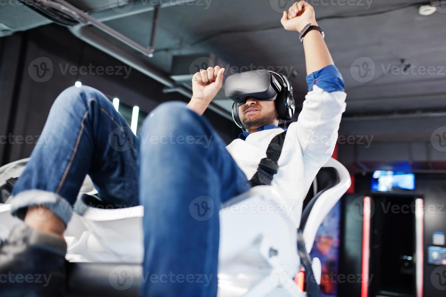 Young indian man having fun with a new technology of a vr headset at virtual reality simulator. photo
