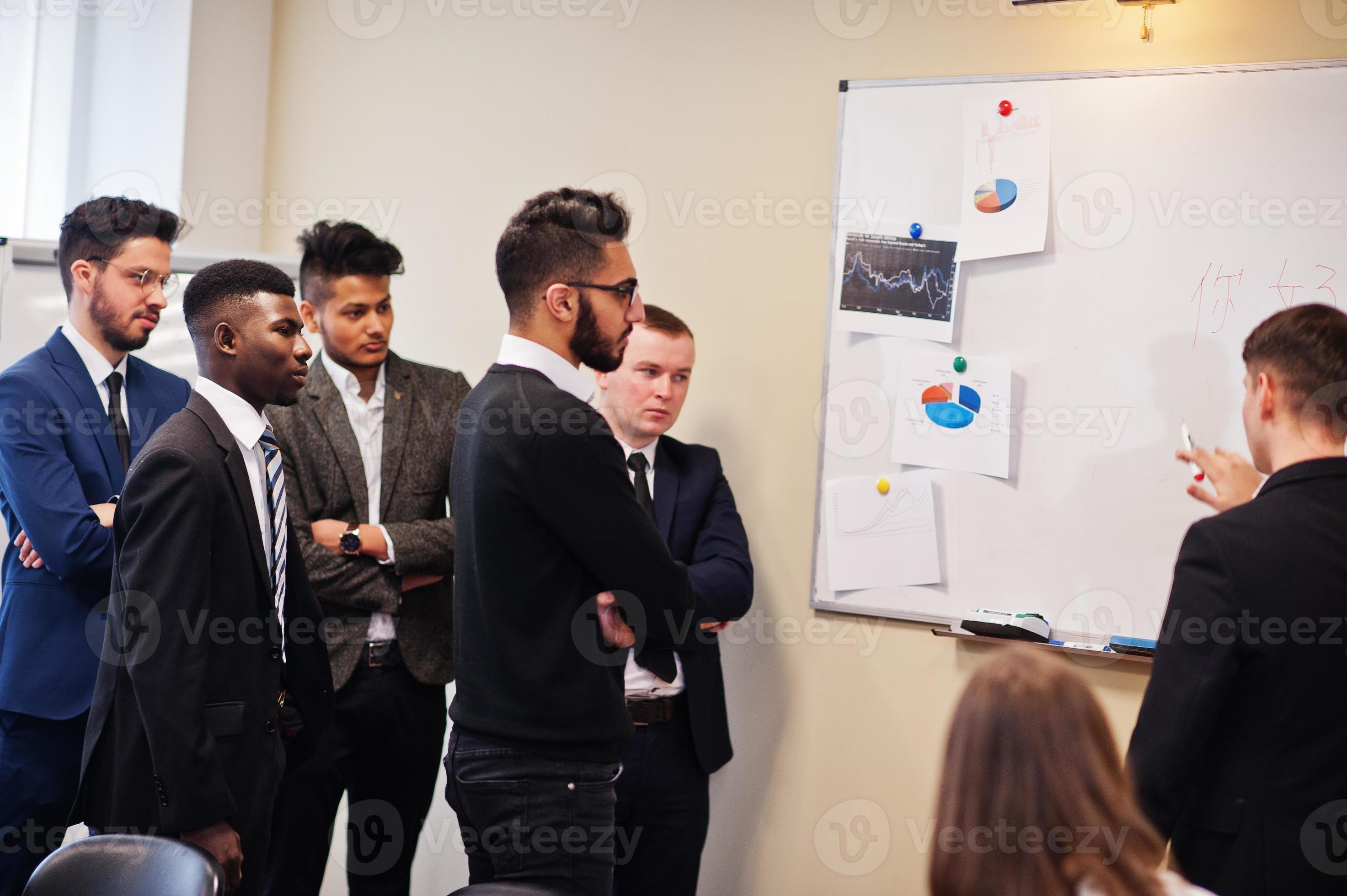 Multiracial business team addressing meeting around boardroom table and