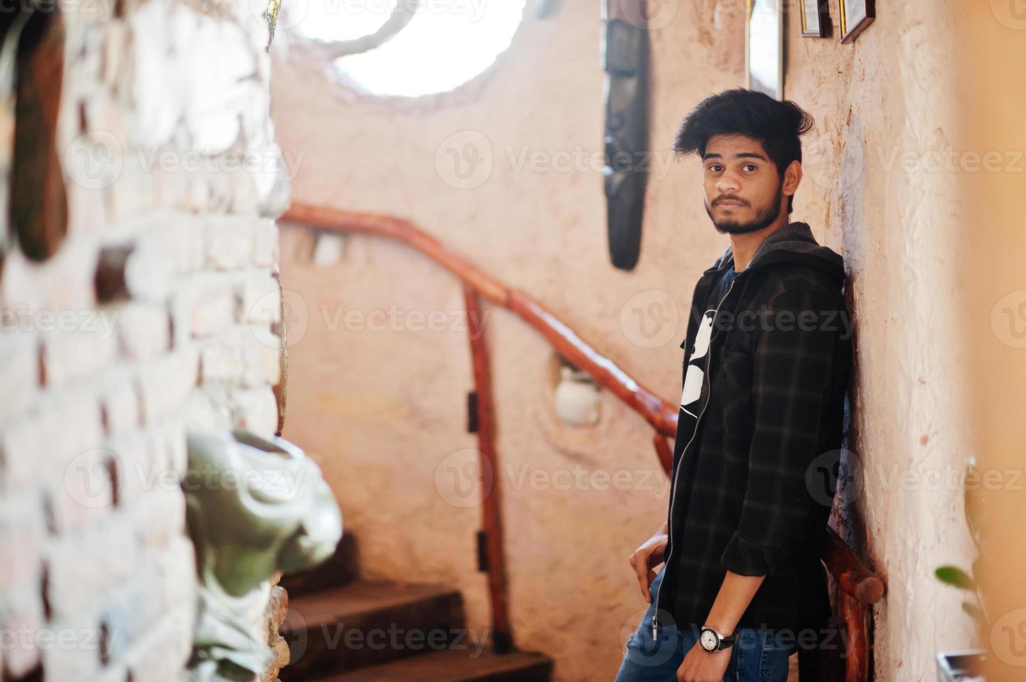 Beard asian man in casual wear stand inside house on stairs against window. photo