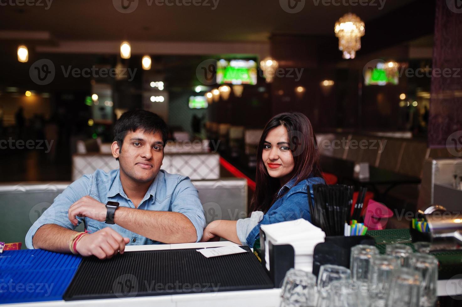 elegante pareja asiática usa jeans sentados en una silla en el bar del club. foto