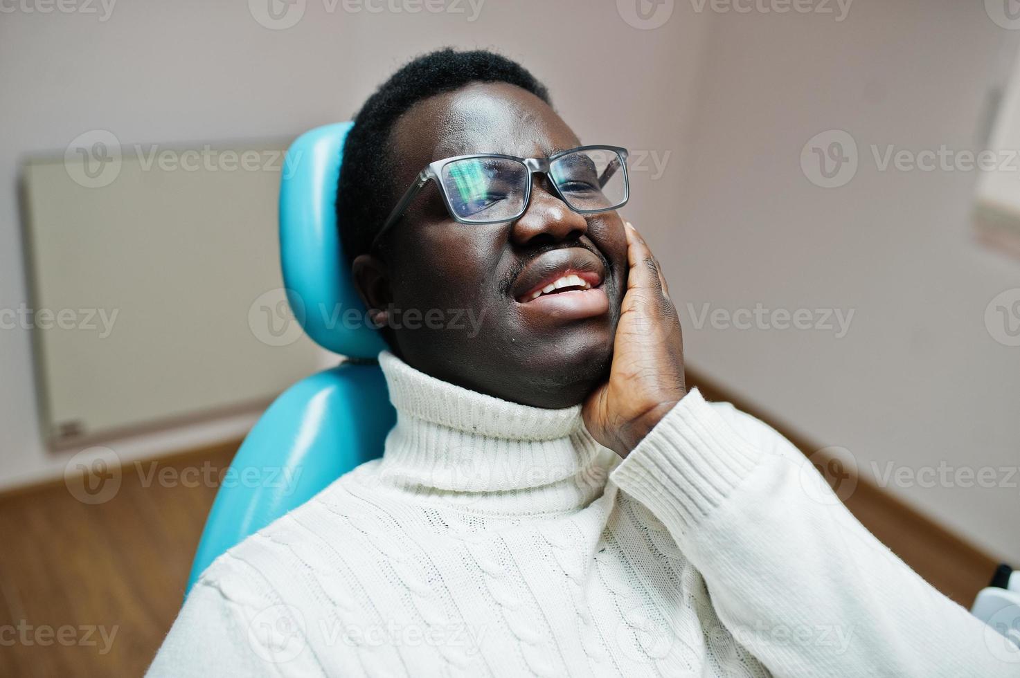 African american man having toothache sitting in a dental chair and need helping, male patient in pain. Dentistry medical. photo