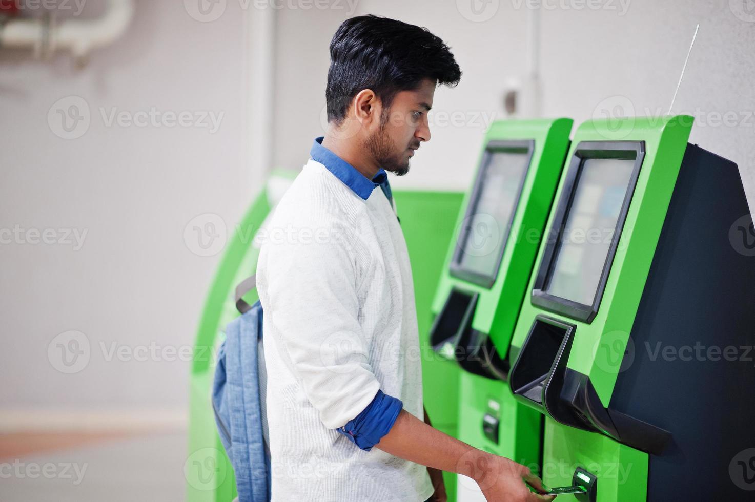 un joven asiático puso su tarjeta de crédito para sacar efectivo de un cajero automático verde. foto