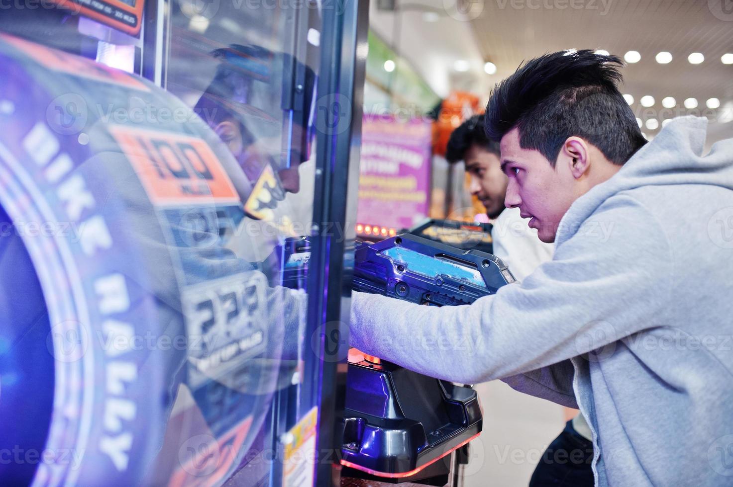 dos chicos asiáticos compiten en una máquina arcade de juegos de simulador de disparos. foto