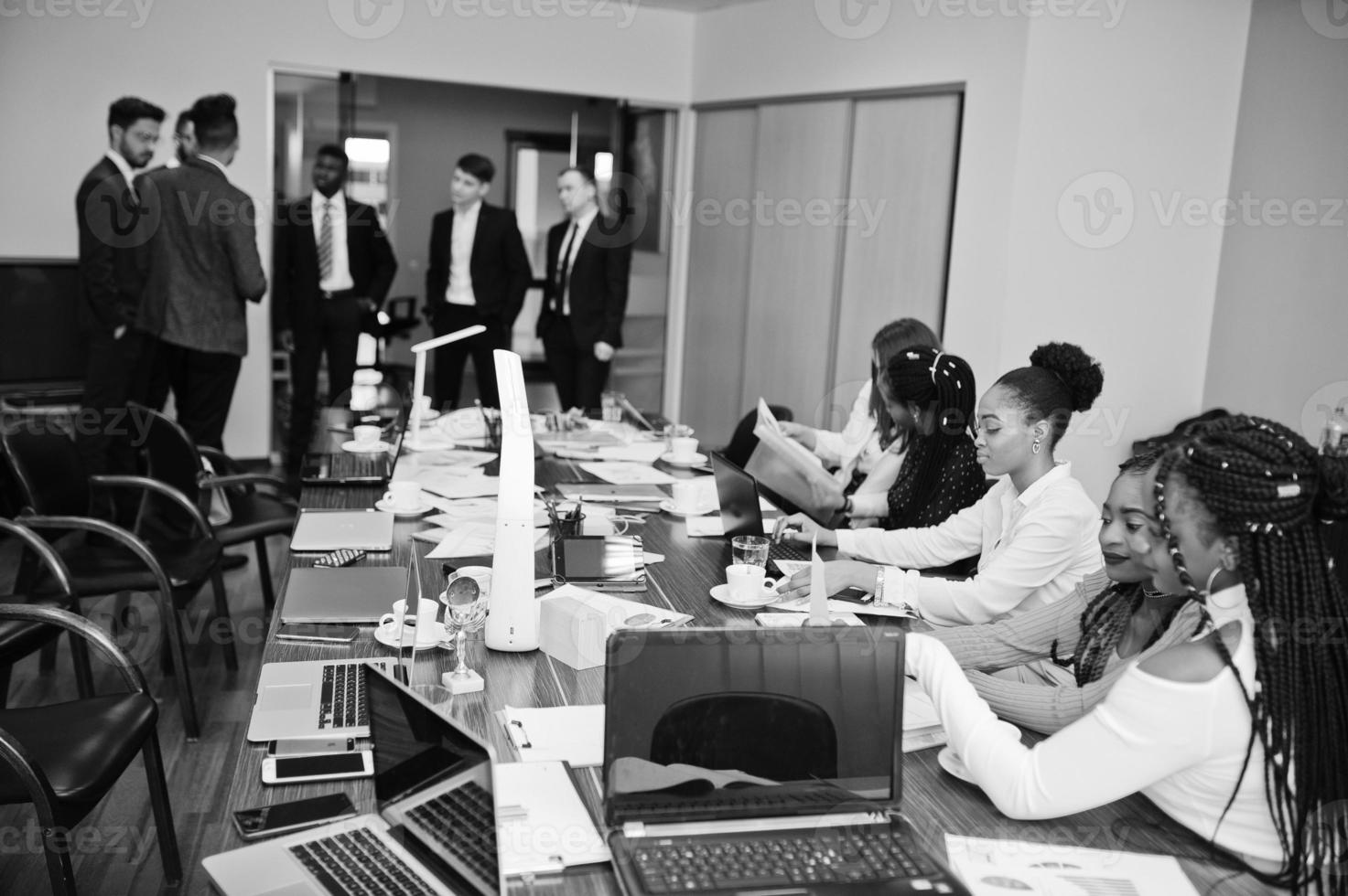 equipo de negocios multirracial que aborda la reunión alrededor de la mesa de juntas. foto