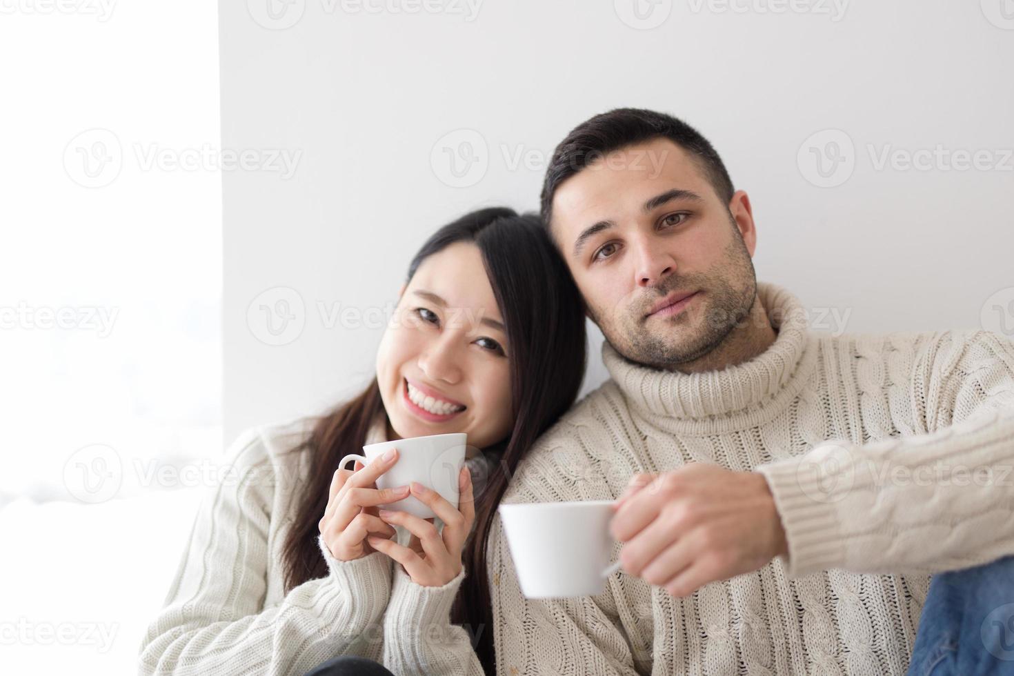 pareja multiétnica disfrutando del café matutino junto a la ventana foto