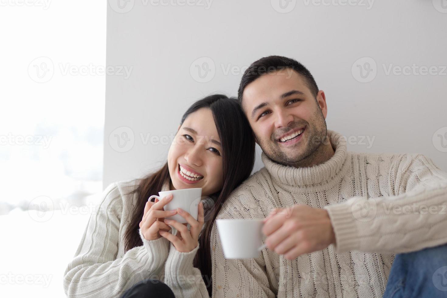 pareja multiétnica disfrutando del café matutino junto a la ventana foto