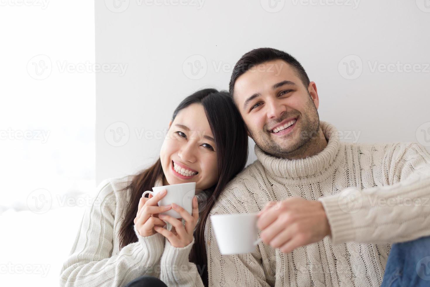 pareja multiétnica disfrutando del café matutino junto a la ventana foto