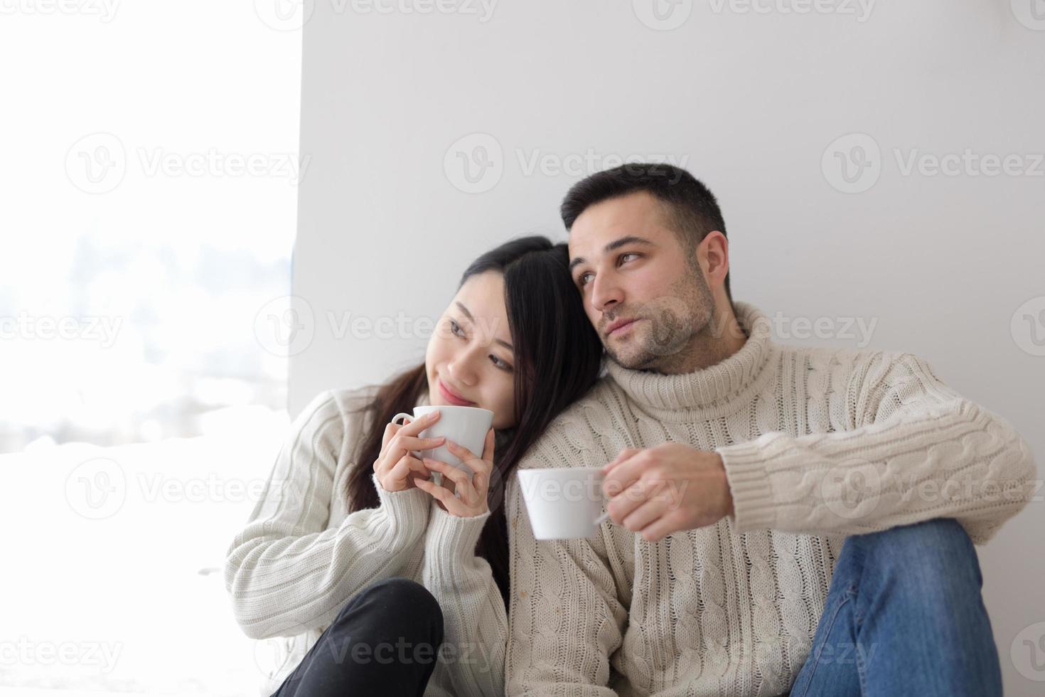 pareja multiétnica disfrutando del café matutino junto a la ventana foto