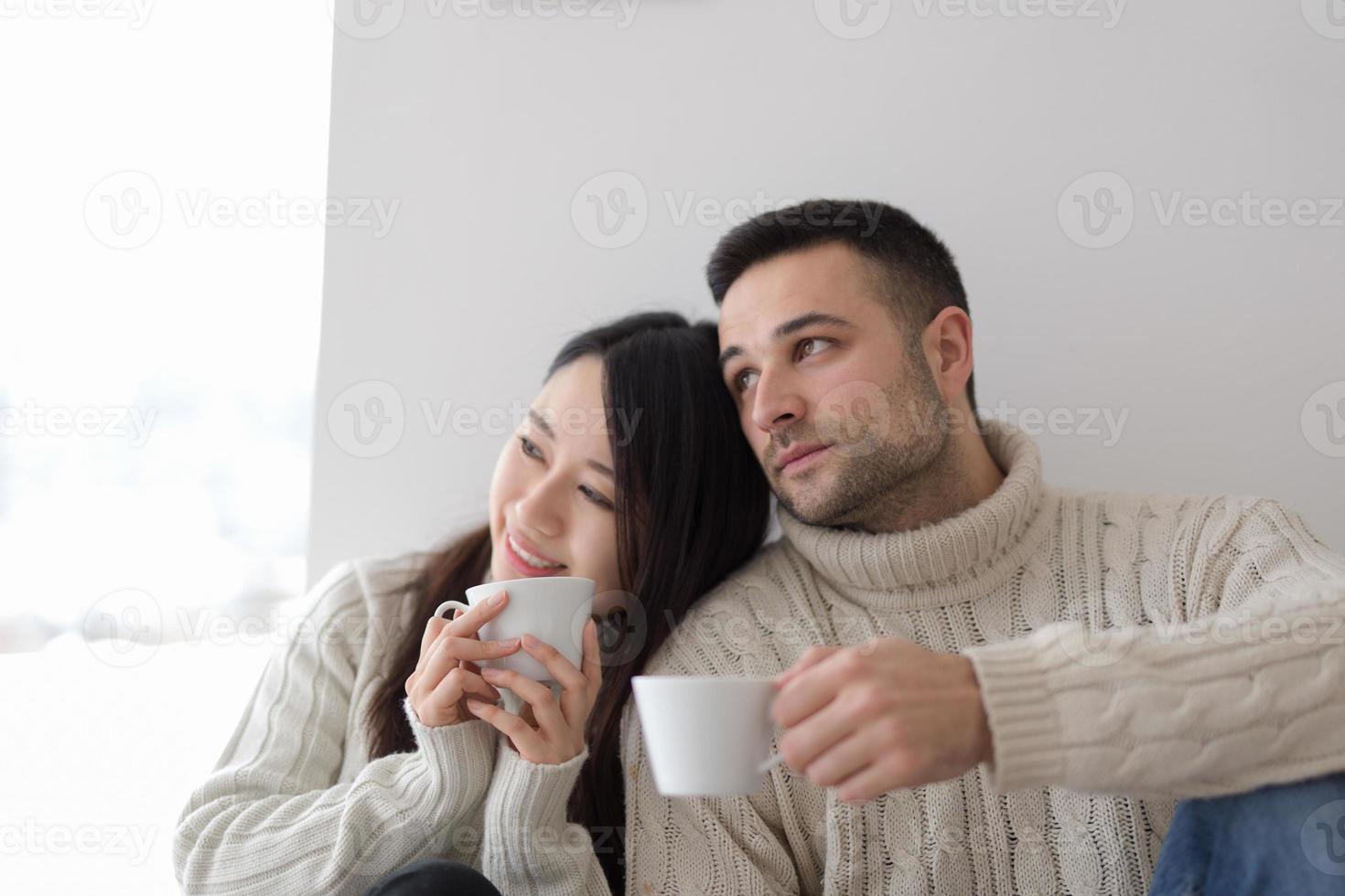 pareja multiétnica disfrutando del café matutino junto a la ventana foto