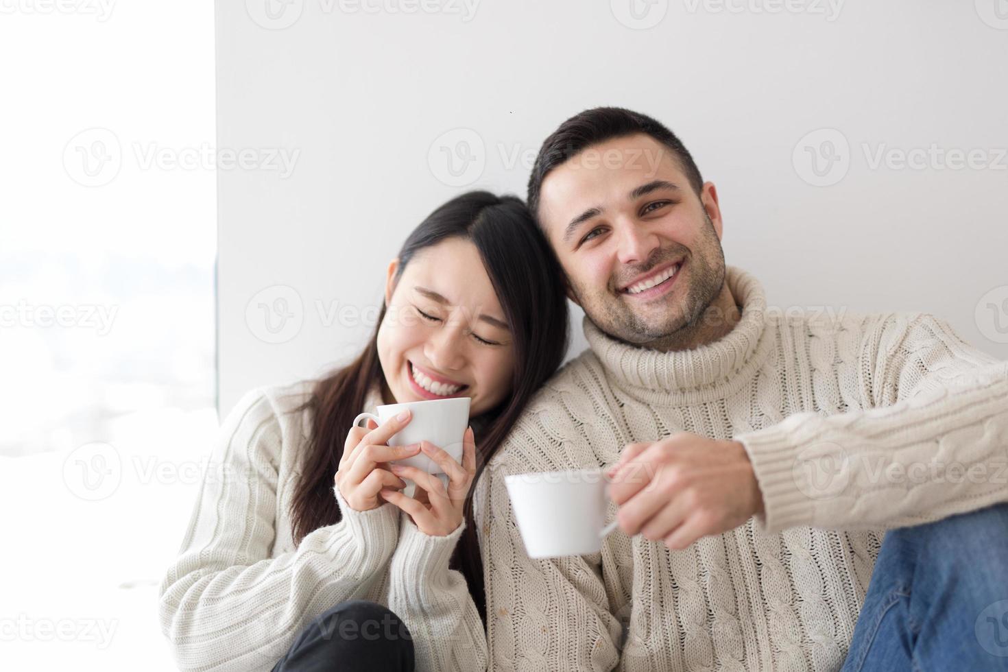 pareja multiétnica disfrutando del café matutino junto a la ventana foto