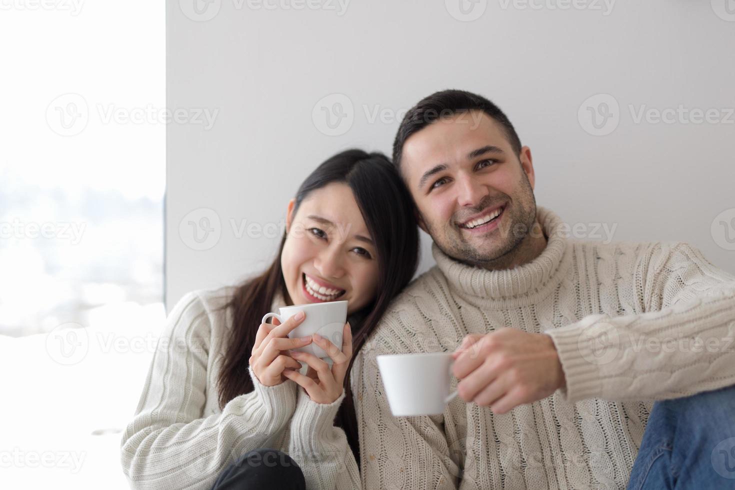 pareja multiétnica disfrutando del café matutino junto a la ventana foto