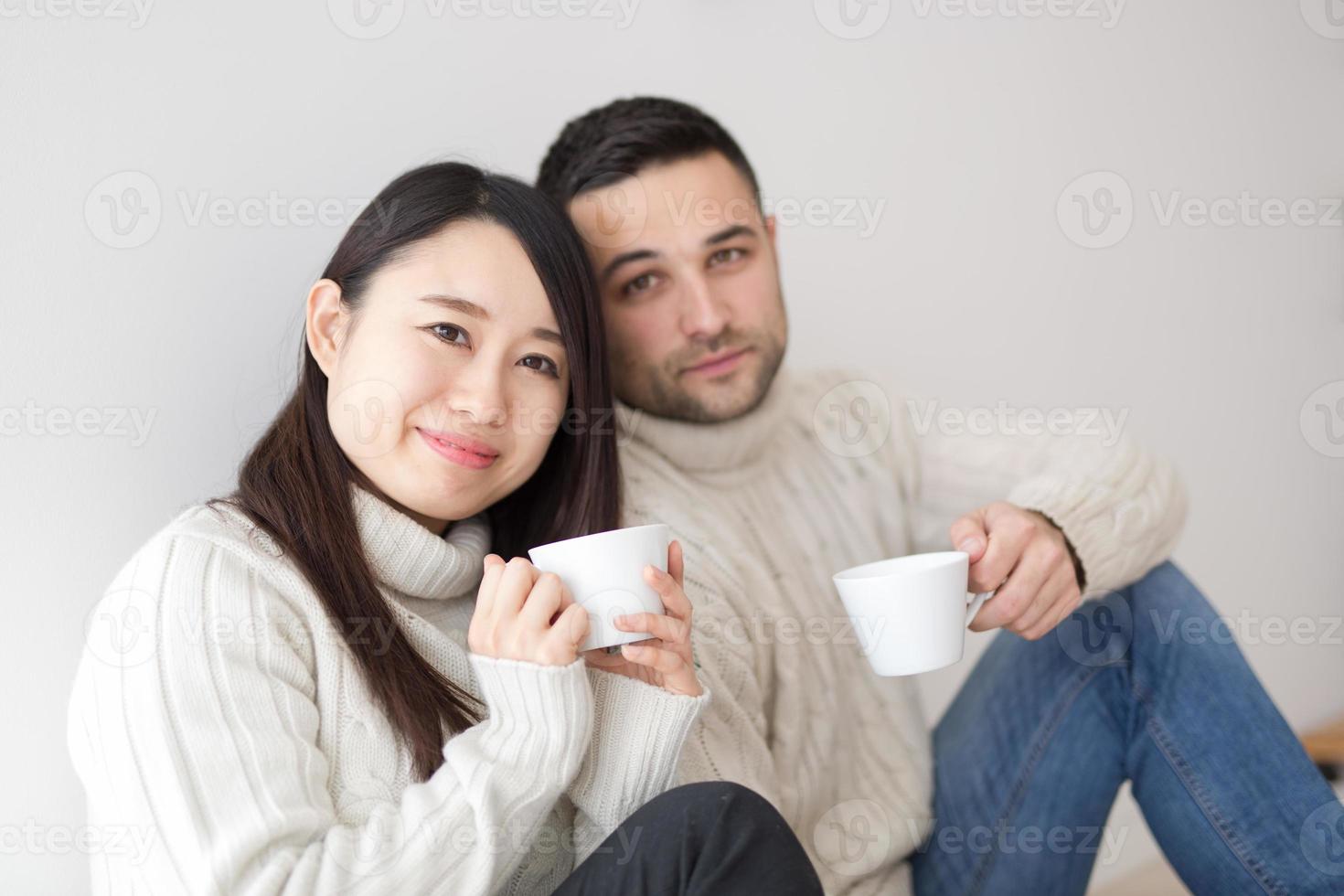 pareja multiétnica disfrutando del café matutino junto a la ventana foto