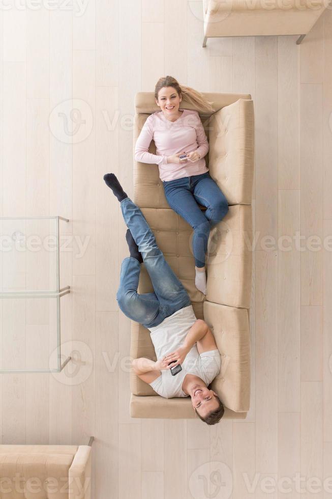 Young couple on the sofa watching television top view photo