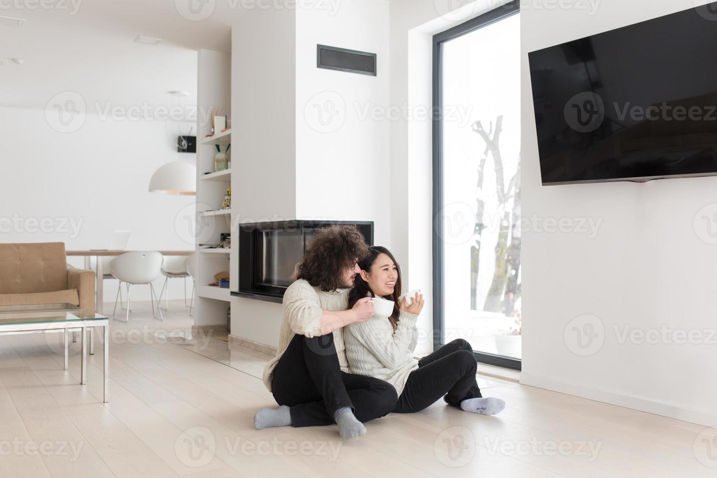 feliz pareja multiétnica frente a la chimenea foto