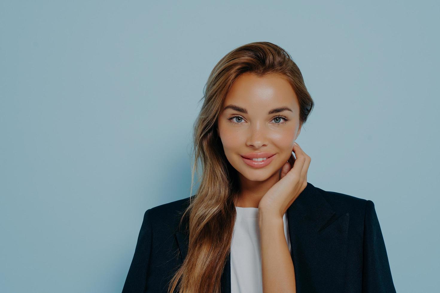 Attractive woman with gentle smile against light blue background photo