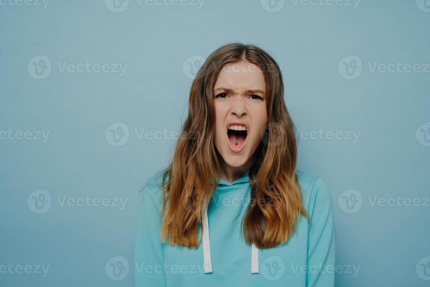 Pretty teenage girl expressing angry disbelief posing isolated over blue background photo