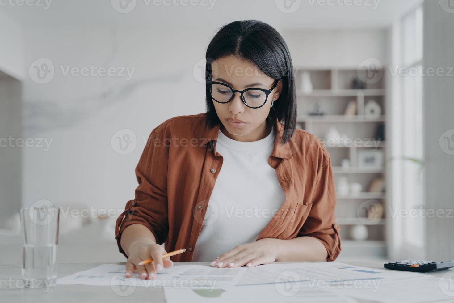 Serious girl, businesswoman is examining reports. Young european woman is working remote from home. photo