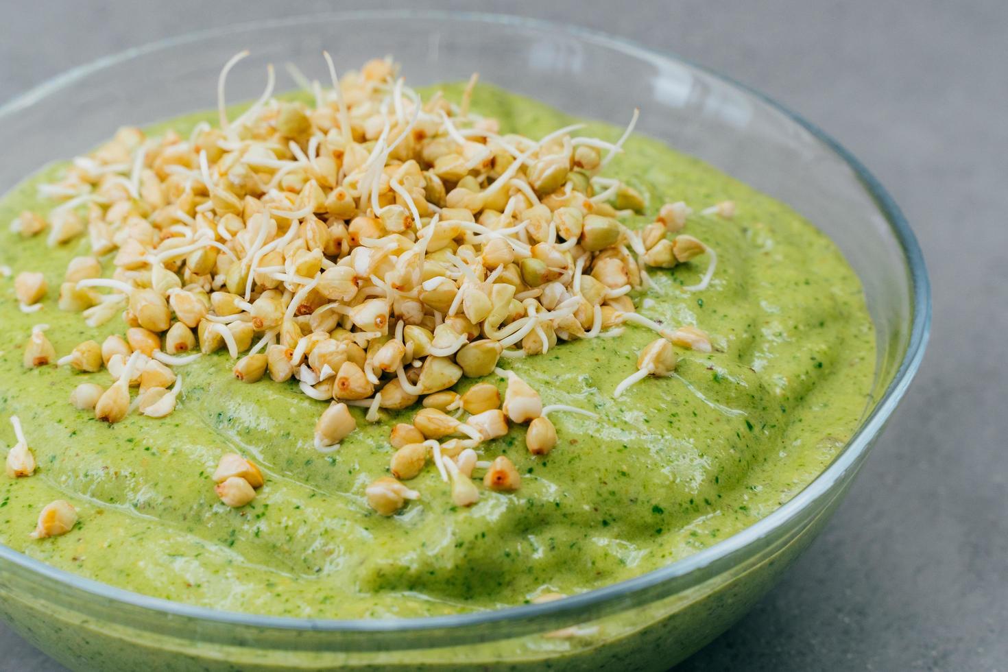 Close up shot of homemade spinach smoothie in bowl covered with buckwheat sprouts. Vegan smoothie. Organic food. Healthy nutrition concept photo