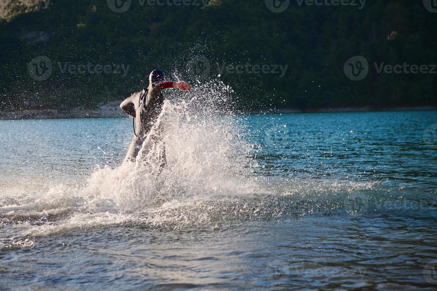 triathlon athlete starting swimming training on lake photo