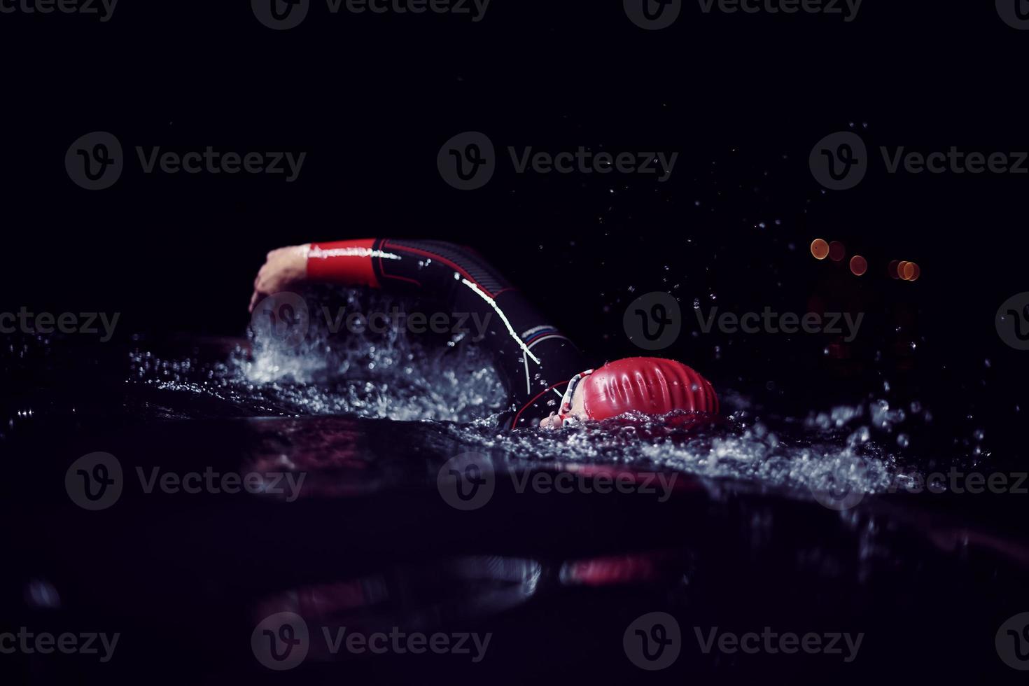 triathlon athlete swimming in dark night  wearing wetsuit photo