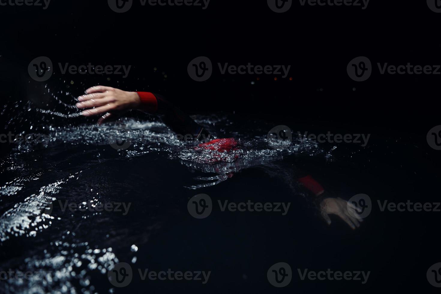 triathlon athlete swimming in dark night  wearing wetsuit photo