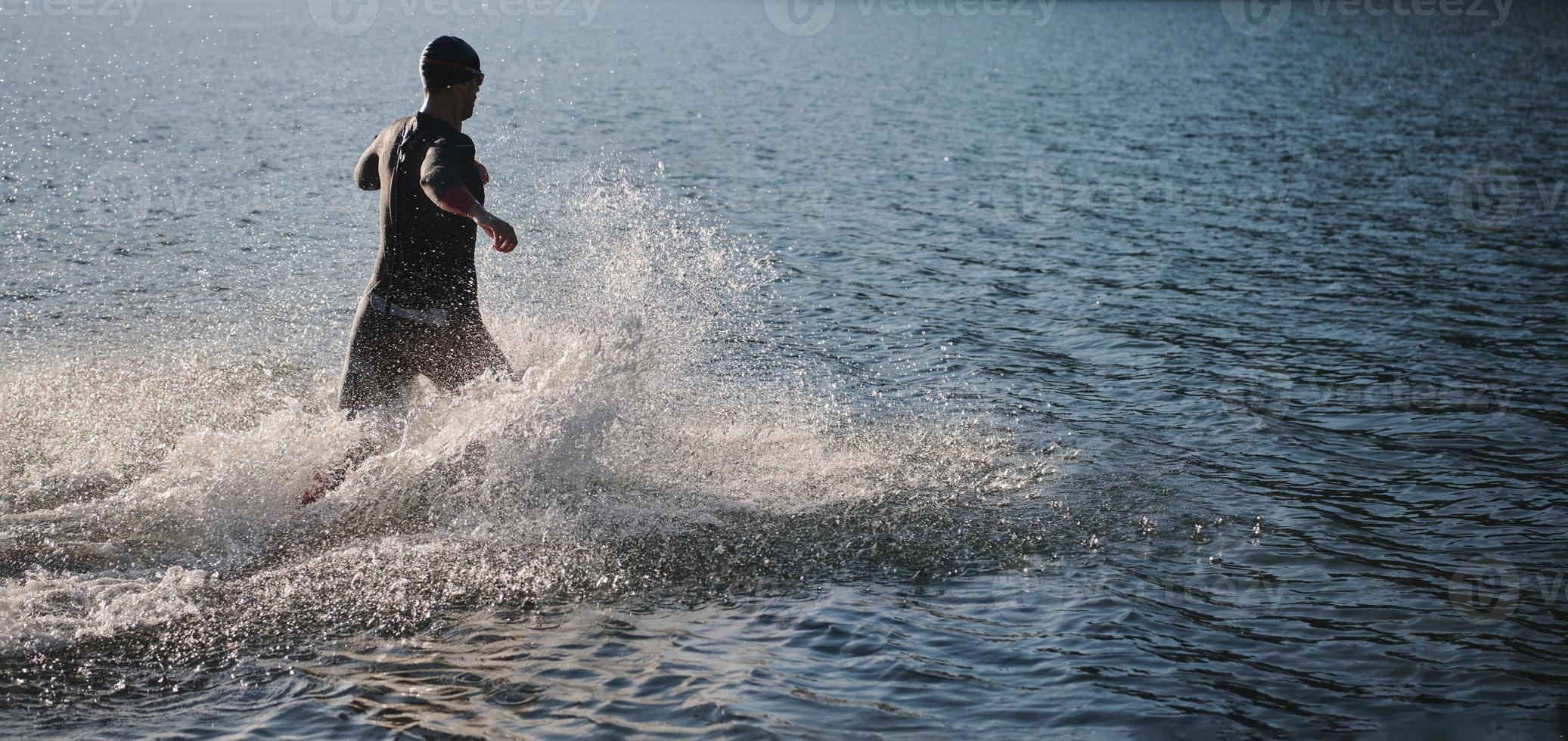triathlon athlete starting swimming training on lake photo