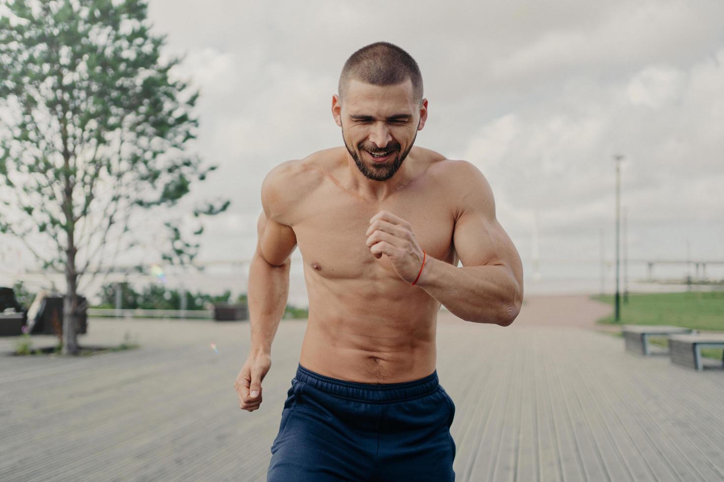 Athletic motivated male jogger takes part in running marathon, has aim to come first on finish, exercises outdoors and trains endurance. Active healthy sportsman has fitness training in morning. photo