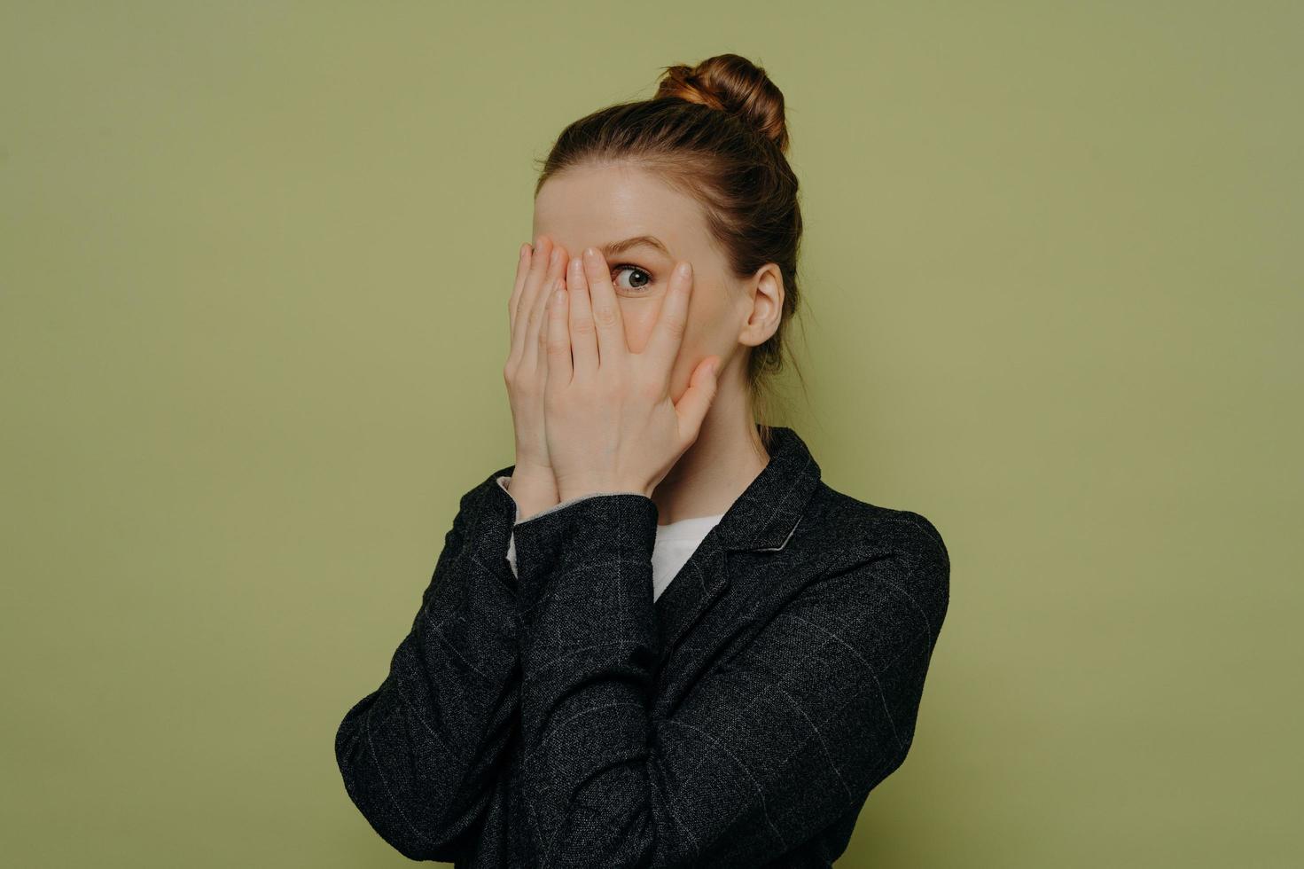 Young woman in formal wear closing face with hands photo