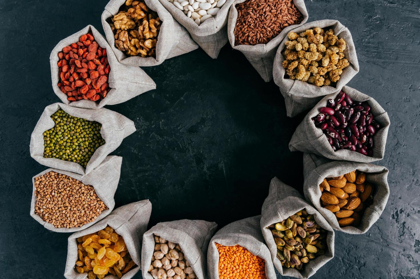 Food and nutrition concept. Horizontal shot of sacks filled with protein rich dried fruits and legumes. Almonds, walnuts, raisins, pink seeds. photo