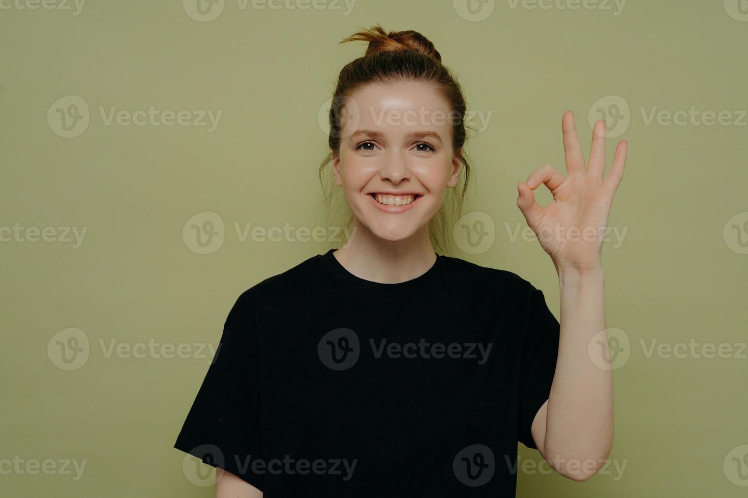 joven mujer alegre con camiseta negra que muestra un gesto correcto foto