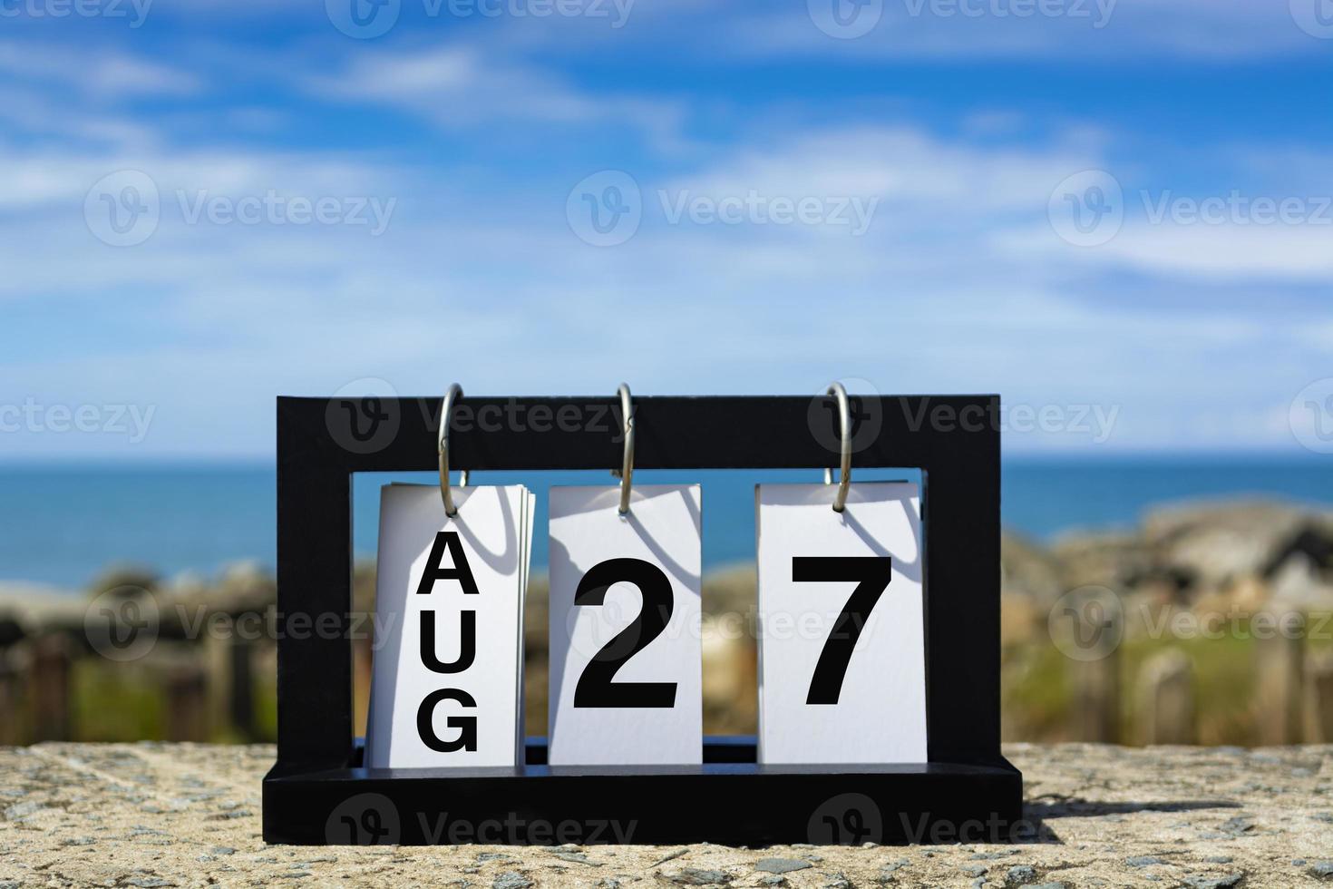 Aug 27 calendar date text on wooden frame with blurred background of ocean. photo