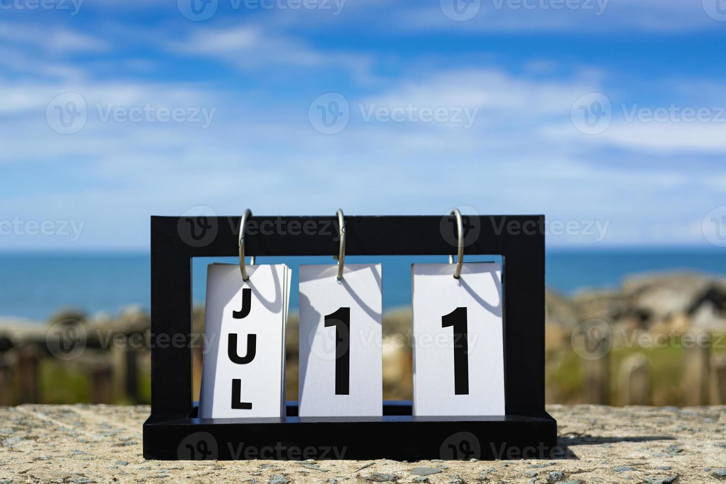 Jul 11 calendar date text on wooden frame with blurred background of ocean. photo